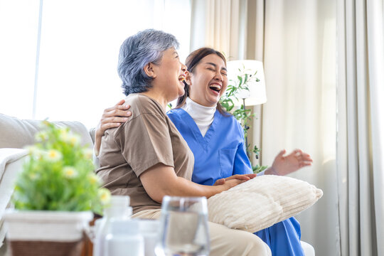 Smiling nurse sharing joyful moment with elderly woman during home caregiving session, expressing empathy, laughter, and companionship that promote mental wellness, recovery, and positive relationship