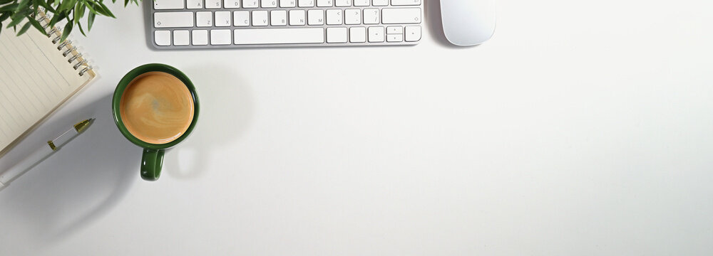 Office desk table with computer, cup of coffee and supplies. Top view with copy space panorama, flat lay.
