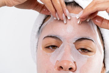 Young woman applying moisturizing facial sheet mask