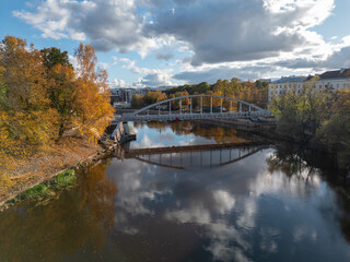 A river landscape with colorful autumn trees and an arched bridge mirrored in calm water.