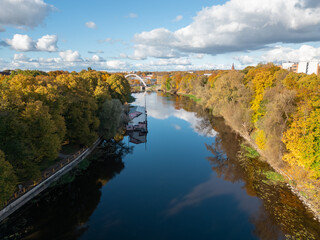 A reflective river scene with autumn trees and an arched bridge glowing in soft light.
