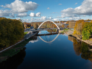 A sweeping autumn river view with an arched bridge reflected in still water.