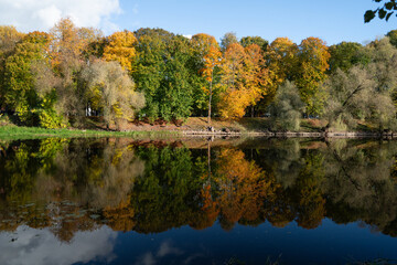 Autumn riverbank with vivid trees reflected in still water.