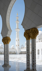 Vertical detail of white mosque minaret framed by white arc, United Arab Emirates