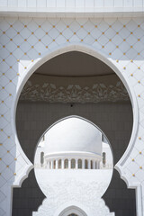 Architectural detail of white mosque framed by shade and arcs, United Arab Emirates