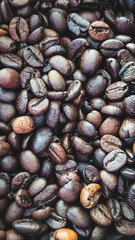 vertical full-frame texture of dark roasted coffee beans with rich color and minimal focus depth