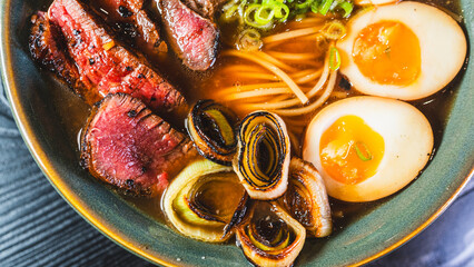 Succulent rare beef ramen in a beautiful bowl with bamboo shoots, spring onions, tamago (Japanese...