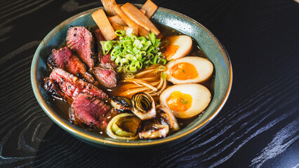 Succulent rare beef ramen in a beautiful bowl with bamboo shoots, spring onions, tamago (Japanese marinated egg), and leeks. Rich broth, authentic Japanese flavors.