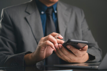 Close-up hand businessman holding smartphone pen. Working office desk. Modern business technology, mobile connectivity, online networking, professional communication, check project data.