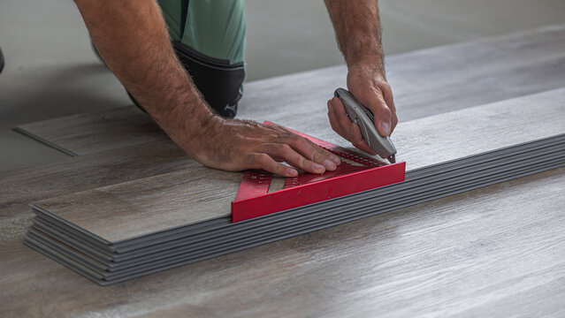 Floating floor work. The worker use utility knife to shortening the board of vinyl plank.
