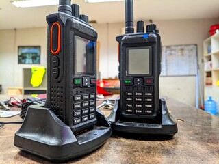 Close-up of two portable walkie talkies on charging docks inside an office, representing communication equipment, technology, coordination, and security in a professional workspace