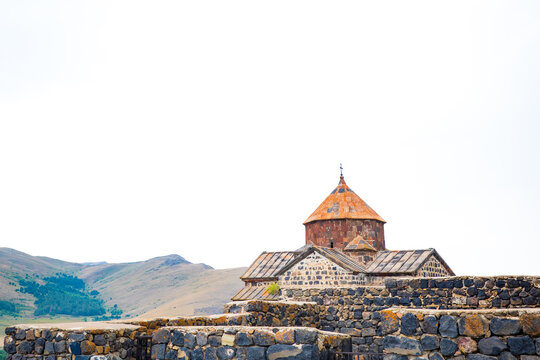 Sevanavank Monastery, an ancient Armenian church made of volcanic basalt and tuff stones, stands gracefully against the mountain backdrop near Lake Sevan