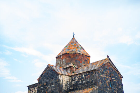 Close-up view of the historic Sevanavank Monastery, the medieval church in Armenia, featuring its distinct orange-and-black volcanic stone dome topped with a cross