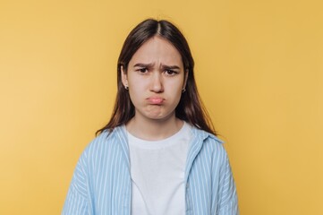 Obraz premium Young woman with a pouty expression against a yellow background.