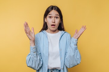 Young woman with surprised expression on yellow background