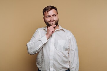 Man in white shirt pondering against a beige background.