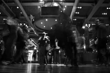 Abstract black and white photo of people dancing in motion blur under city lights. Dynamic nightlife and artistic movement captured in low light