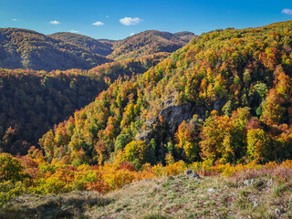 Bright autumn forest seen from the Hetem&eacute;r Rock Shelter area, overlooking the rugged cliffs of V&ouml;r&ouml;s-kő and the B&uuml;kk Plateau under a clear blue sky.