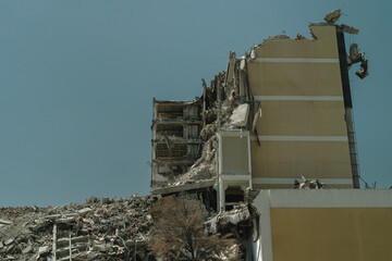 Severely damaged multi-story building surrounded by debris, because of demolition, collapse, or post-disaster scene. 