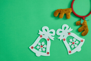 White Christmas bells with red snowflake decorations and reindeer antlers headband on a green background