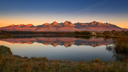 Naklejka premium High Tatras reflected in the lake at sunset in autumn