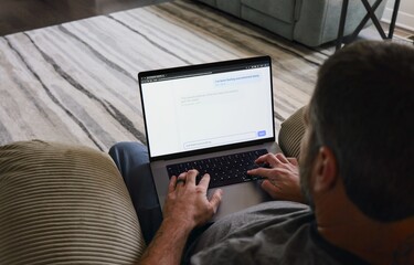 Middle Aged Man in Tan Recliner Texting AI Chatbot