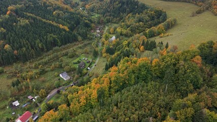 Aerial mountain valley village Travna Czechia autumn descend. Czech Republic or Czechia historically known as Bohemia. Central Europe. Autumn fall season, brilliant colorful leaves along roads.