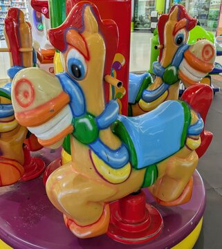 Juguete autom&aacute;tico de atracci&oacute;n por monedas. Vista de cerca de caballitos de vivos colores de una atracci&oacute;n infantil  con carrusel, instalada en un centro comercial