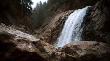A powerful waterfall cascades down a rugged rocky cliff face in a dense forest