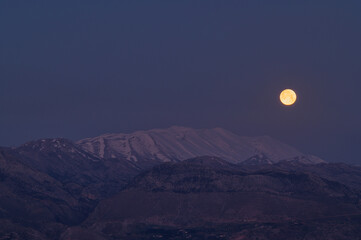 Full moon rising over snow capped Mount Psiloritis in Crete 