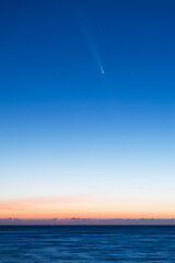 Bright comet over calm sea at sunrise twilight sky