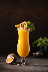 Passion Fruit and mango cocktail or juice in hurricane glass on black background. Vertical format. Traditional healthy drink with mango. Freshness lassi made of yogurt, water, spices, fruits and ice.