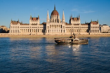 Naklejka premium Hungarian Parliament Building during sunset with a boat