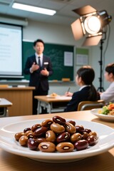 Asian male teacher leading classroom discussion with students and healthy snacks