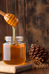Honey jar and honey dipper on wooden background	