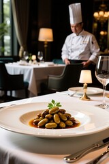 Chef in elegant restaurant setting with gourmet dish of olives in rich sauce
