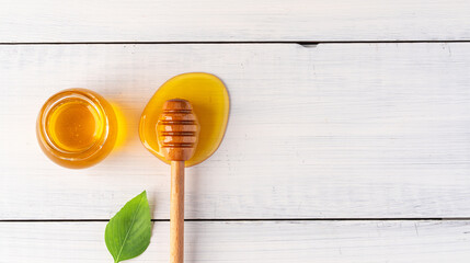 Honey jar and  honey dipper  on white wooden background