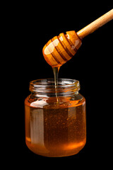 Honey jar and  honey dipper  on black  background