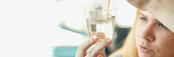 Caucasian female adult conducting water quality test with glass container and tool.