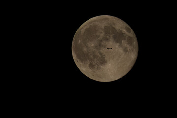 Aufnahme einer Flugzeugsilhouette vor dem Mond.