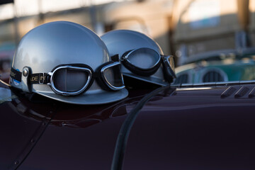 Aufnahme von zwei klassischen Helmen mit Brille auf einer Motorhaube.