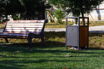 Park bench and waste bin located in a neatly maintained green space on a sunny day