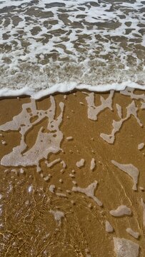 Sea foam and waves on golden sand beach