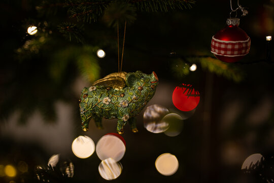 Green pig Christmas ornament on decorated tree with lights