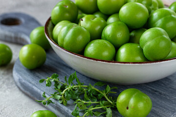 Tkemali, green cherry plum, in a bowl, on a gray table, top view, natural light, no people,