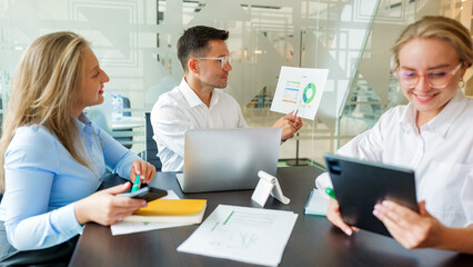 Team members discuss business strategy with charts during a meeting in a modern office space