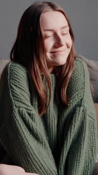 Attractive young lady in a comfortable green sweater, beaming with joy, captured in a peaceful moment. A delightful portrait of a lovely woman savoring a serene interlude