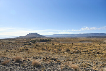 Traveling through the province of Neuquen, Argentina, during wintertime. Low vegetation in the foreground, mountains in the background.