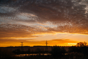 Naklejka premium power lines in a field at a beautiful sunrise