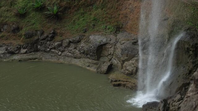October 23, 2025; Ellora Caves, Maharashtra, India: A high-angle view of a waterfall cascading down a mossy rock cliff into a tranquil plunge pool below.